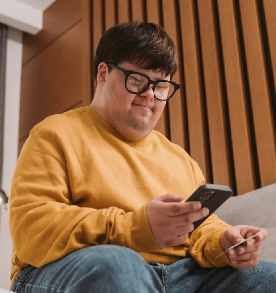 Jeune homme souriant qui tient un téléphone et une carte de crédit